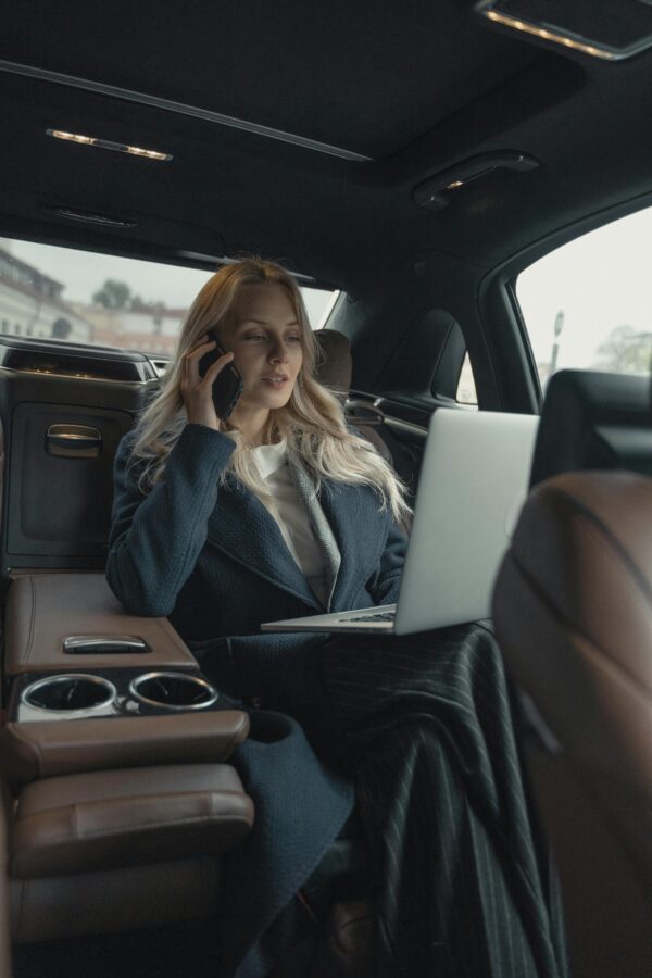 pexels-photo-5717641-5717641 Confident businesswoman making a call and working on a laptop in a luxury car interior.